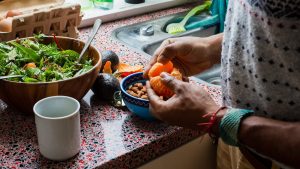 person holding orange fruit on blue ceramic bowl
